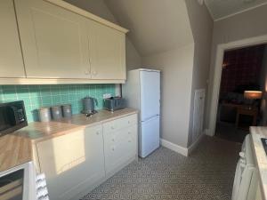 a kitchen with white cabinets and a blue refrigerator at PERGOLA Cottage in Melrose +7 photos