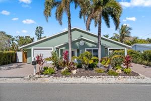 a house with palm trees in front of it at Enclosed pool spa - Stillpoint by SeaBreeze Vacation in Holmes Beach