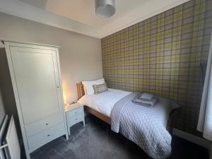 a small bedroom with a bed and a cabinet at PERGOLA Cottage in Melrose