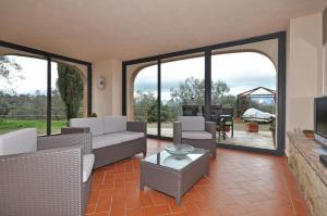 a living room with a couch and chairs and a tv at Guardistallo by PosarelliVillas in Guardistallo