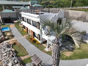 a house with a palm tree in front of it at ALY HOTEL See Sea Son in Kure