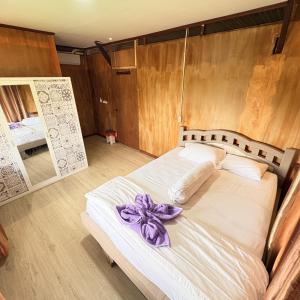 a bedroom with a bed with a purple bow on it at Rumsram Homestay by Rumah Etnik Papua Sorong in Papermaranda