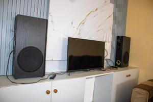 a tv on top of a cabinet with two speakers at Ziwa View Apartments in Goat Island