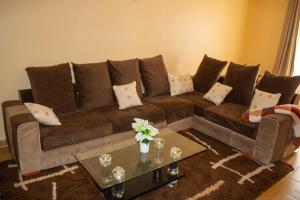 a living room with a brown couch and a table at Ziwa View Apartments in Goat Island