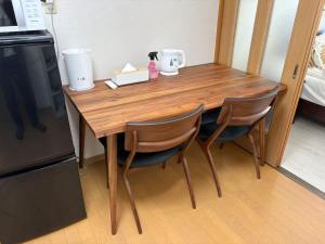 ein Holztisch mit zwei Stühlen in einer Küche in der Unterkunft MUTSUMI Hotel in Saga