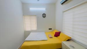a small bedroom with a yellow bed and a window at Sign Valley in Cochin