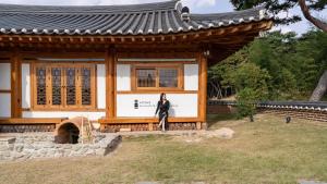 a woman is standing in front of a building at Gyeongju Oru Hanok Stay in Gyeongju