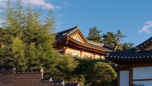 a building with a roof with trees in front of it at Gyeongju Oru Hanok Stay in Gyeongju +28 photos