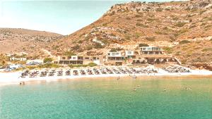 ein Strand mit Stühlen und Sonnenschirmen und ein Resort in der Unterkunft Spathi Beach Suites Kea in Spathi 