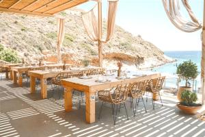 Eine Gruppe von Tischen und Stühlen auf einer Terrasse mit Blick auf das Meer in der Unterkunft Spathi Beach Suites Kea in Spathi  + 14 Fotos