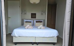 a bedroom with a white bed with towels on it at Luxe Tiny Suite met privé tuinbad in Meerssen