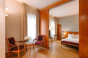 Habitación de hotel con cama, mesa y sillas en Windsor Hotel Milano en Milán