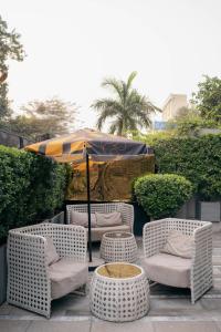 eine Terrasse mit Stühlen, einem Sonnenschirm und einem Tisch in der Unterkunft Ambiance Boutique Art Hotel Lahore in Lahore