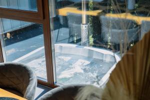 a hot tub sitting inside of a window at Nessa Chalet in Moara de Pădure +22 photos