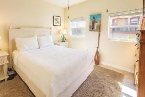 a bedroom with a white bed and two windows at Four Bedroom Two Level Home Near Beach in South Padre Island