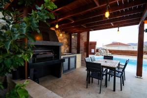 a patio with a table and a grill and a pool at Villa Flam in Kholi