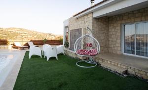 a patio with white chairs and a bird cage on the grass at Villa Flam in Kholi +52 photos