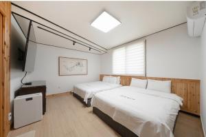a bedroom with two beds and a television in it at Jeonju Dalbitsori Pension in Jeonju