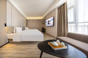a hotel room with a large bed and a couch at Atour Hotel Jinan High-tech Wanda Plaza Tiancheng Road in Jinan