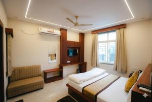 a bedroom with a bed and a couch and a window at The Gripa Hotels in Chitrakoot