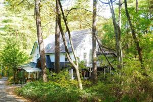 a white house in the middle of trees at はじまりの宿 ディール in Tsumagoi