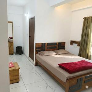 a bedroom with a bed with a red blanket on it at SAIS LINE Residency in Kozhikode