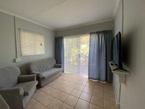 a living room with a couch and a tv at Beach Cresent Cottage in Port Alfred