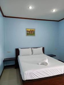 a white bed in a room with a blue wall at ทิพ ทิพ รีสอร์ท ถ้ำเสือ in Ban Krabi Yai