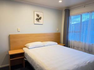 a bedroom with a large bed and a window at Abode Motel in Palmerston North