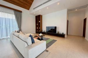 a living room with a couch and a tv at Bougainvillea Luxury Pool Villas in Ban Pak Lak