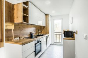 a kitchen with white cabinets and a sink and a tv at Apartments CRYSTAL AURA in Bohinj