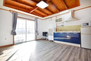 a large kitchen with blue cabinets and a large window at Taean Mong And Mong Pension in Taean