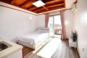 a bedroom with a bed and a television and a window at Taean Mong And Mong Pension in Taean