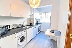 a kitchen with white cabinets and a washer and dryer at Contemporary Chic with Terrace & Balcony in Madrid