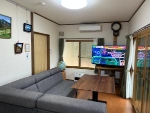a living room with a couch and a flat screen tv at ANBAEE Private Mountain Villa あんばええ in Nakatsugawa