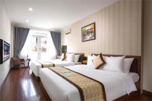 a hotel room with two beds and a couch at Hanoi Spoon Boutique Hotel in Hanoi