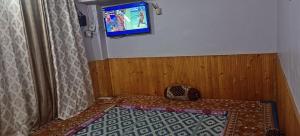 a room with a bed and a tv on a wall at Alavyahomestay in Kilba