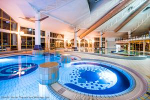 a large swimming pool in a large building at EHM - Modernes Apartment nahe Therme & Natur in Mesteri