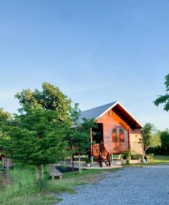 a wooden cabin with a porch and a tree at Rang Robin Farmstay for 4 with pool in Ban Wang Muang