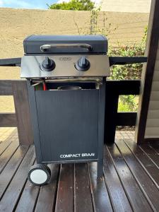 Ein Grill steht auf einer Holzterrasse in der Unterkunft Timmerstuga in Malelane