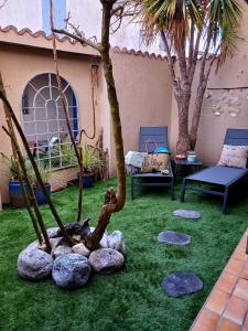 a garden with a palm tree and rocks at Le Clos de Saint Georges in Saint-Georges-dʼOléron