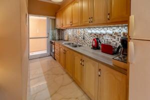 a kitchen with wooden cabinets and a refrigerator at Seafront Apartment with Panoramic Rooftop Terrace in Paramonas