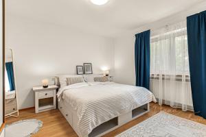 a white bedroom with a bed and blue curtains at Vila Ochutnej Pálavu in Pavlov