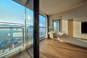 a room with a desk with a view of the city at DeLaSea Ha Long Hotel - Modern Bayview Escape in Ha Long