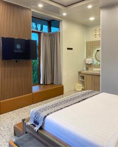 a bedroom with a bed and a tv on a wall at De Pointé Resort & Resto in Campaka