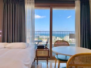 a bedroom with a bed and a table and a balcony at Blue Terra Sokcho in Sokcho +291 photos
