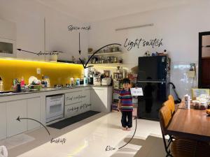 a little boy standing in a kitchen with a refrigerator at Anhbnb in Danang +3 photos