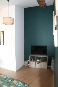 a living room with a television on a cabinet at Chambre Au clos des auges in Saint-Saturnin-du-Bois