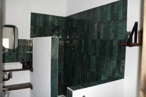 a bathroom with green tile on the wall at Chambre Au clos des auges in Saint-Saturnin-du-Bois +3 photos