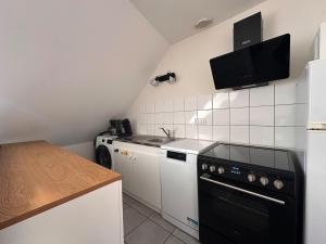 a small kitchen with a black stove and a sink at Murat - La petite maison Murataise in Murat